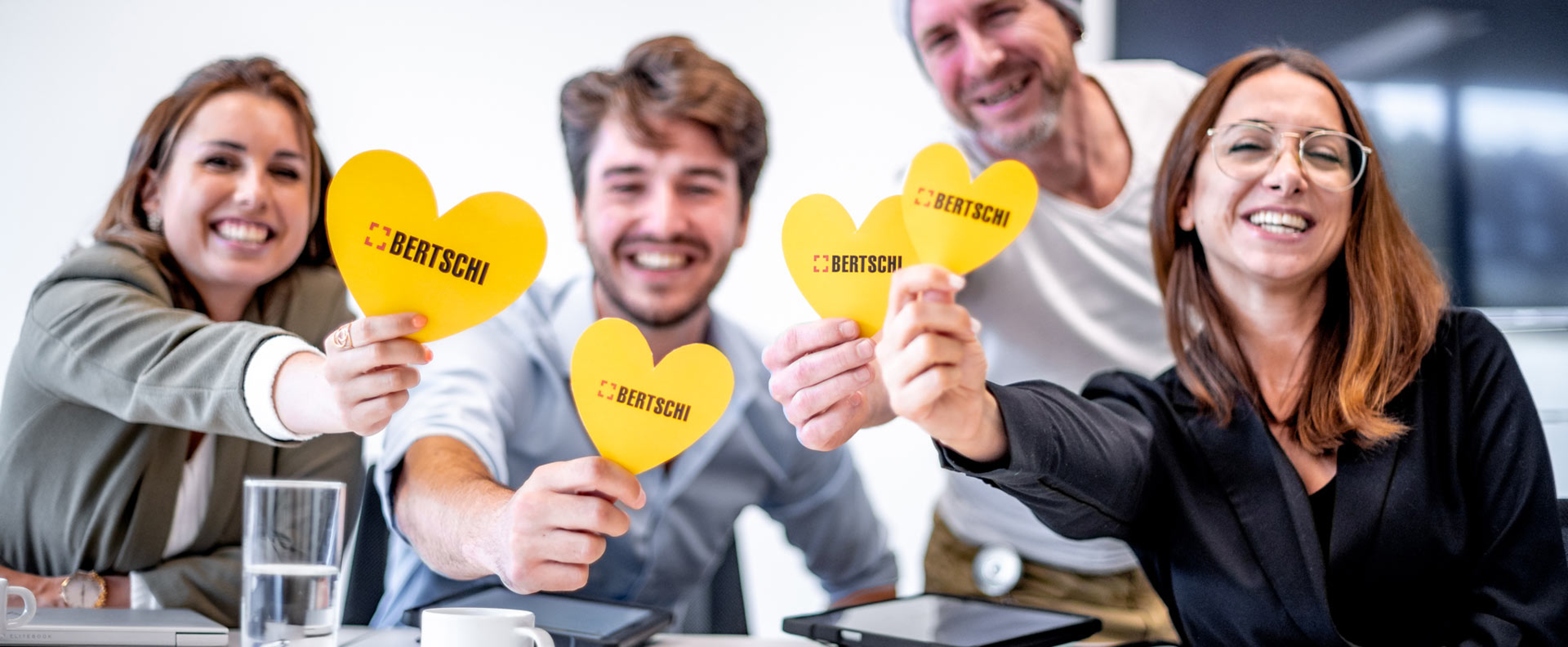 Bertschi Employees holding yellow hearts and smiling into the camera