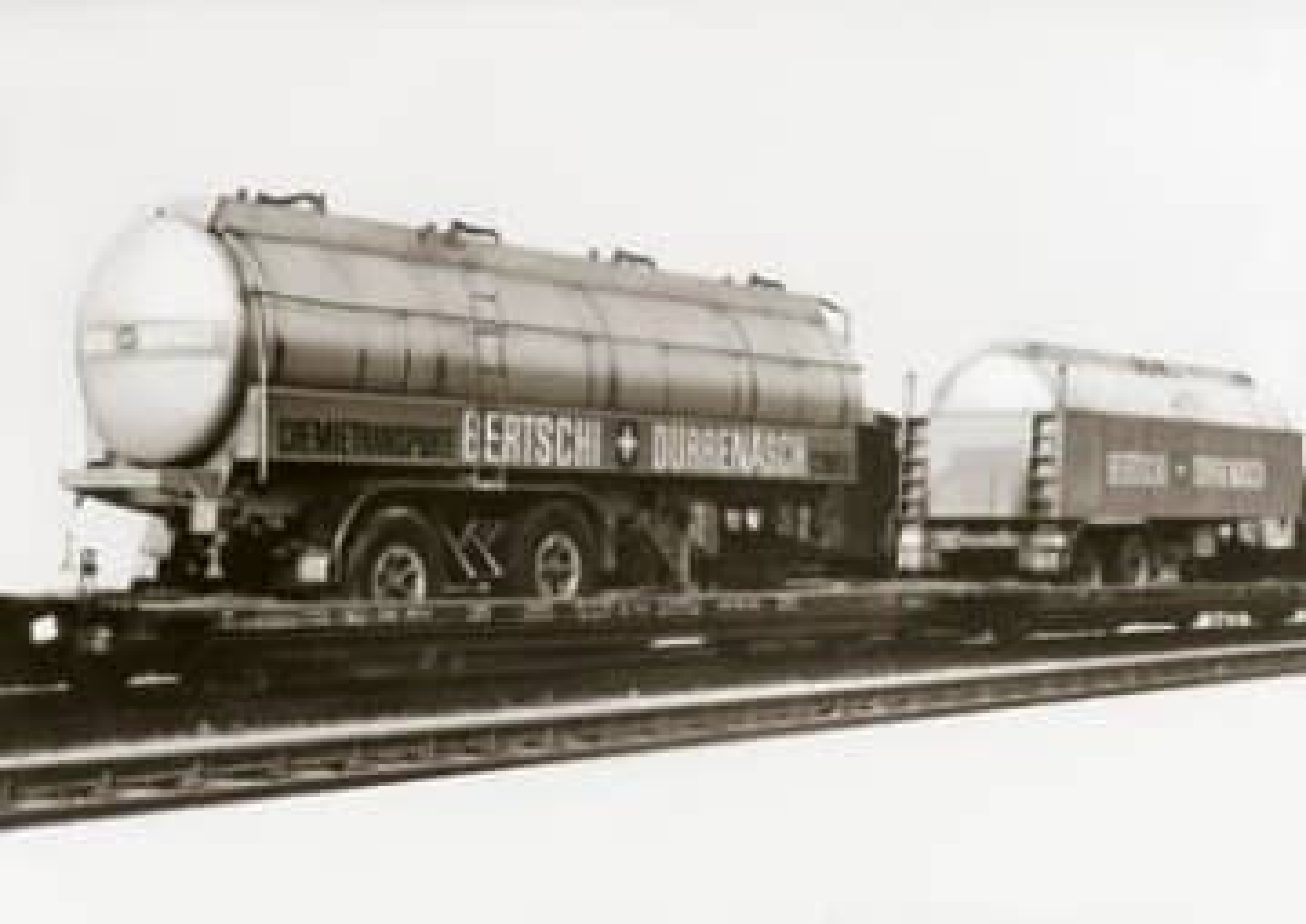 A black and white image of several Bertschi tanking trailers loaded onto railway carts at the newly founded HUPAC terminal.
