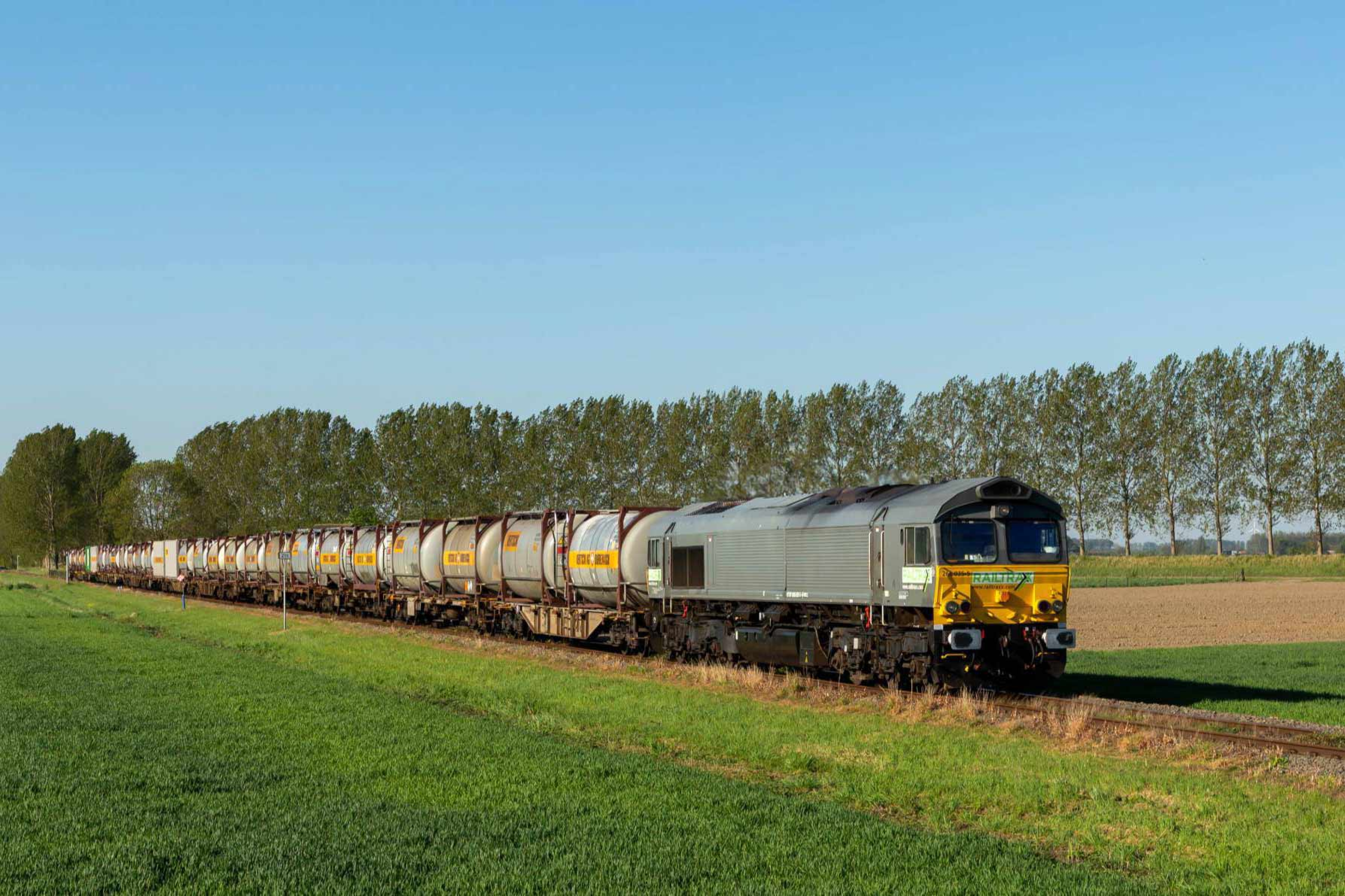 Cargo train with Bertschi containers surrounded by trees and fields