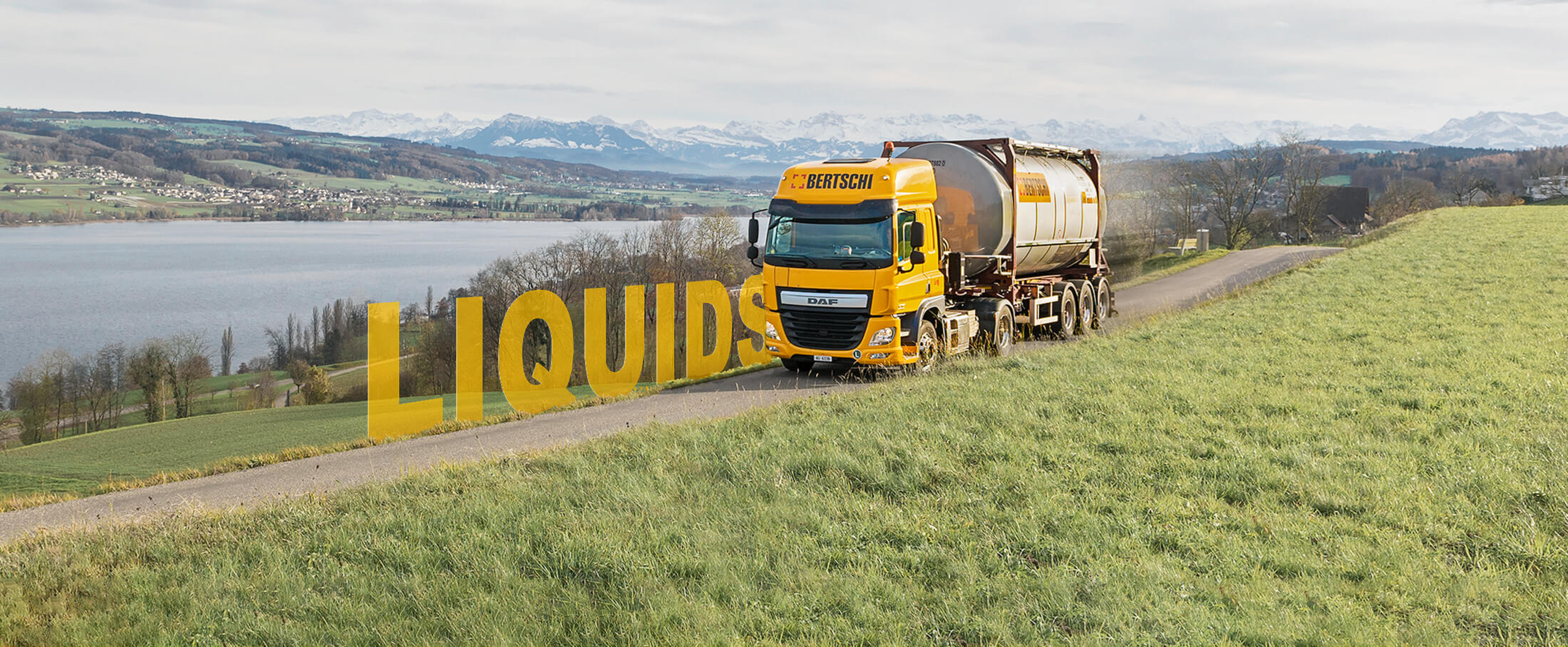 A Bertschi truck carrying a liquid container driving over a country road