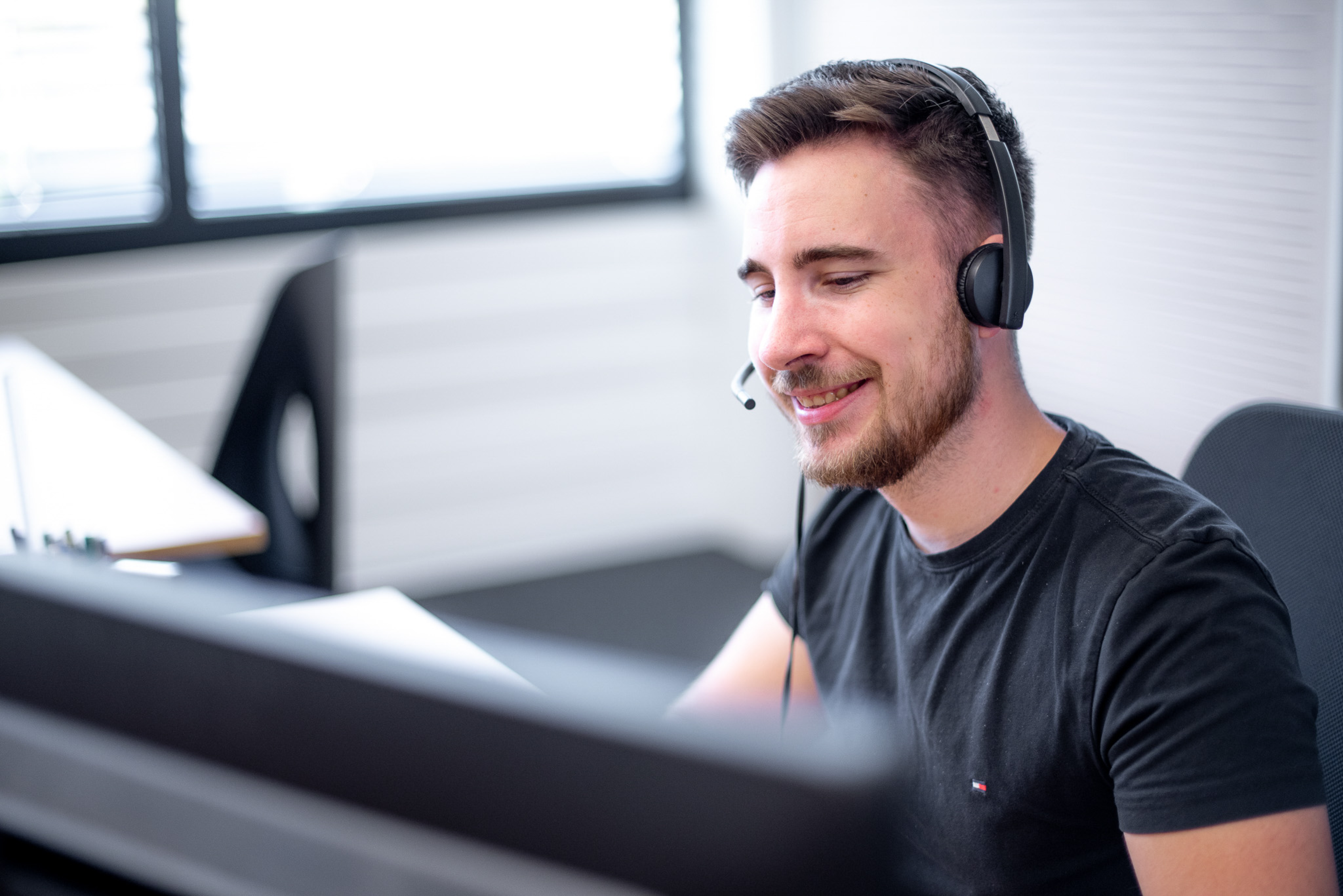 Employee with headset smiling at the computer