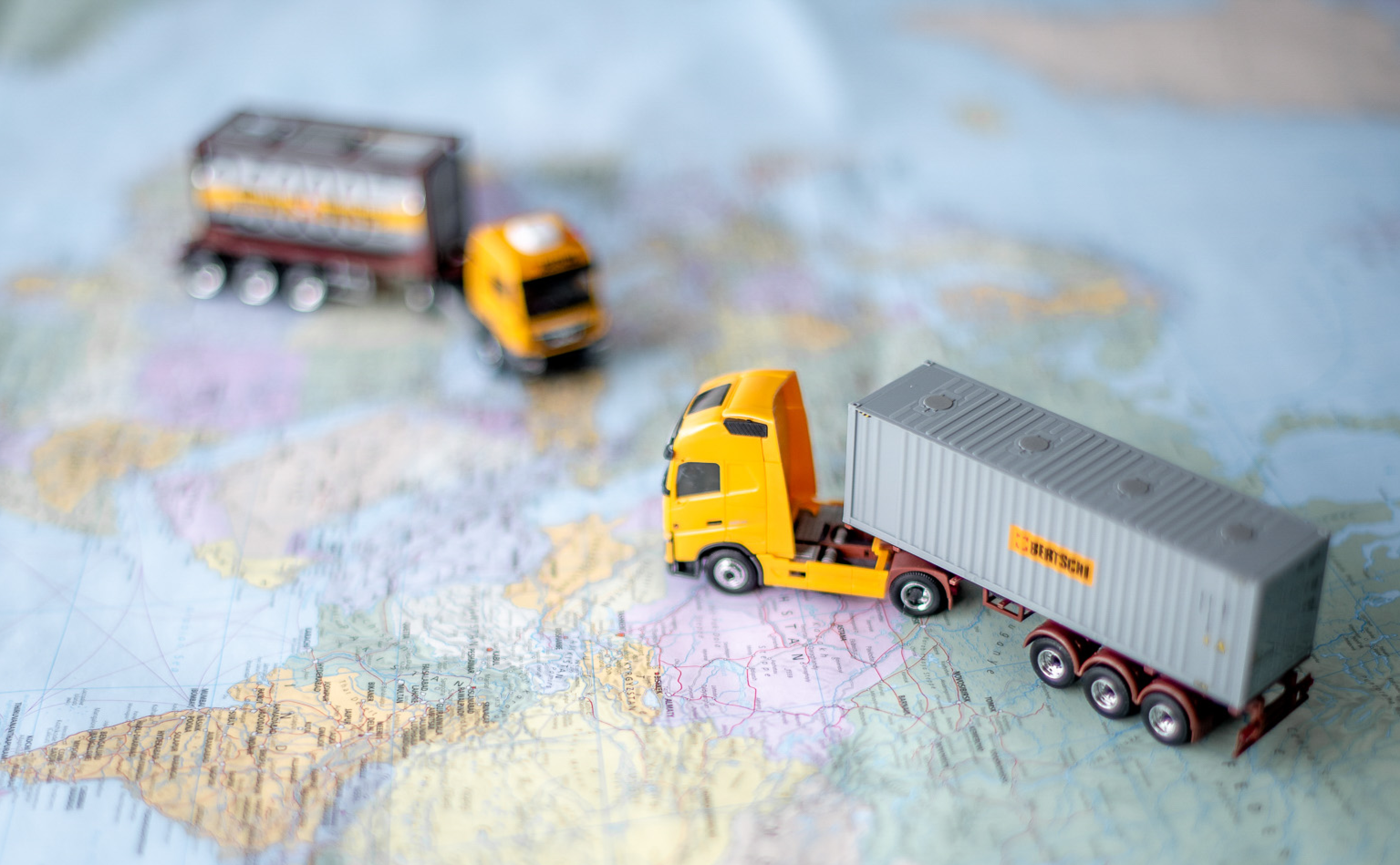 two scale model trucks on a worls map on a table