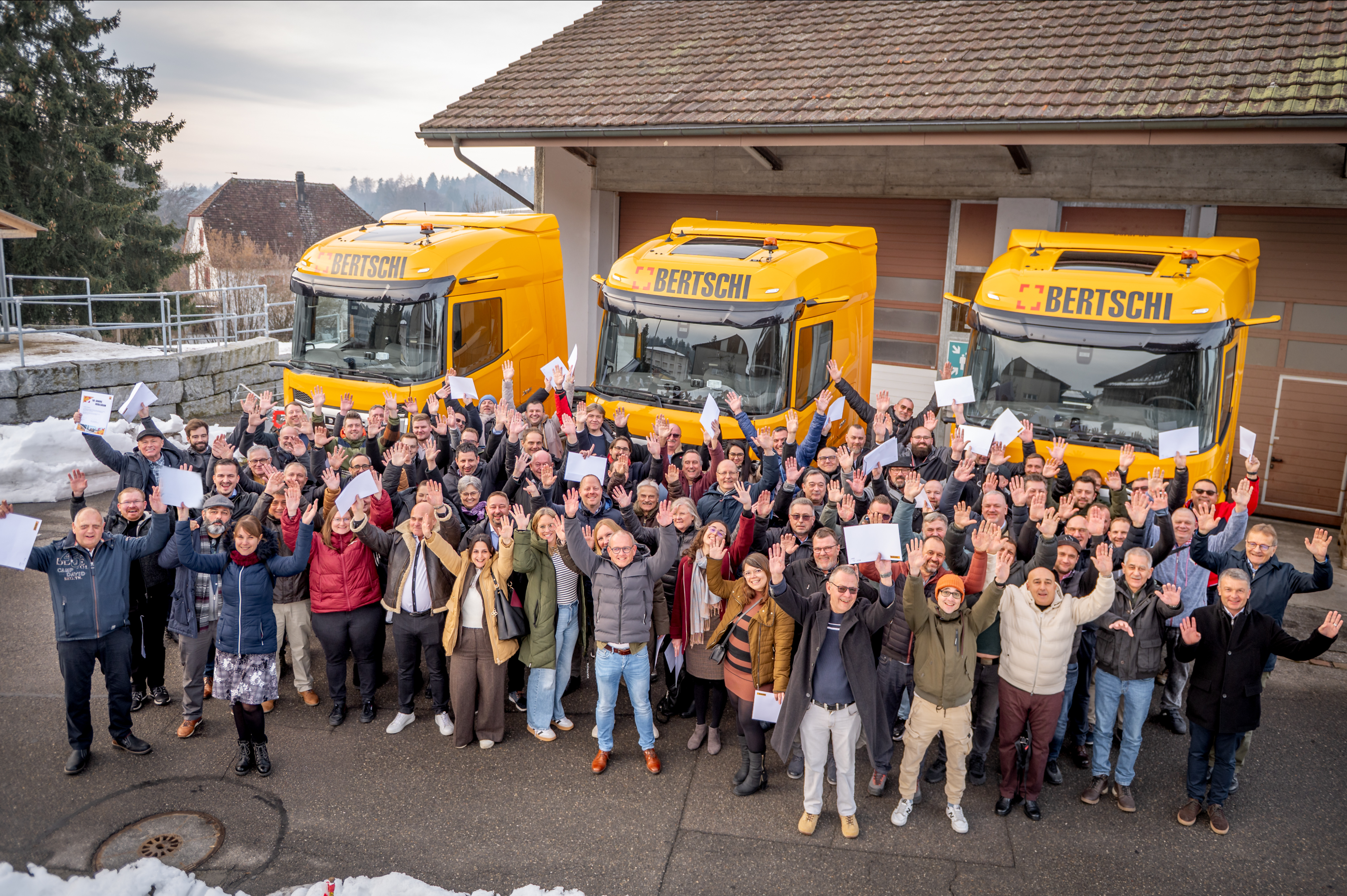 153 employees celebrating their anniversaries standing in front of three Bertschi trucks