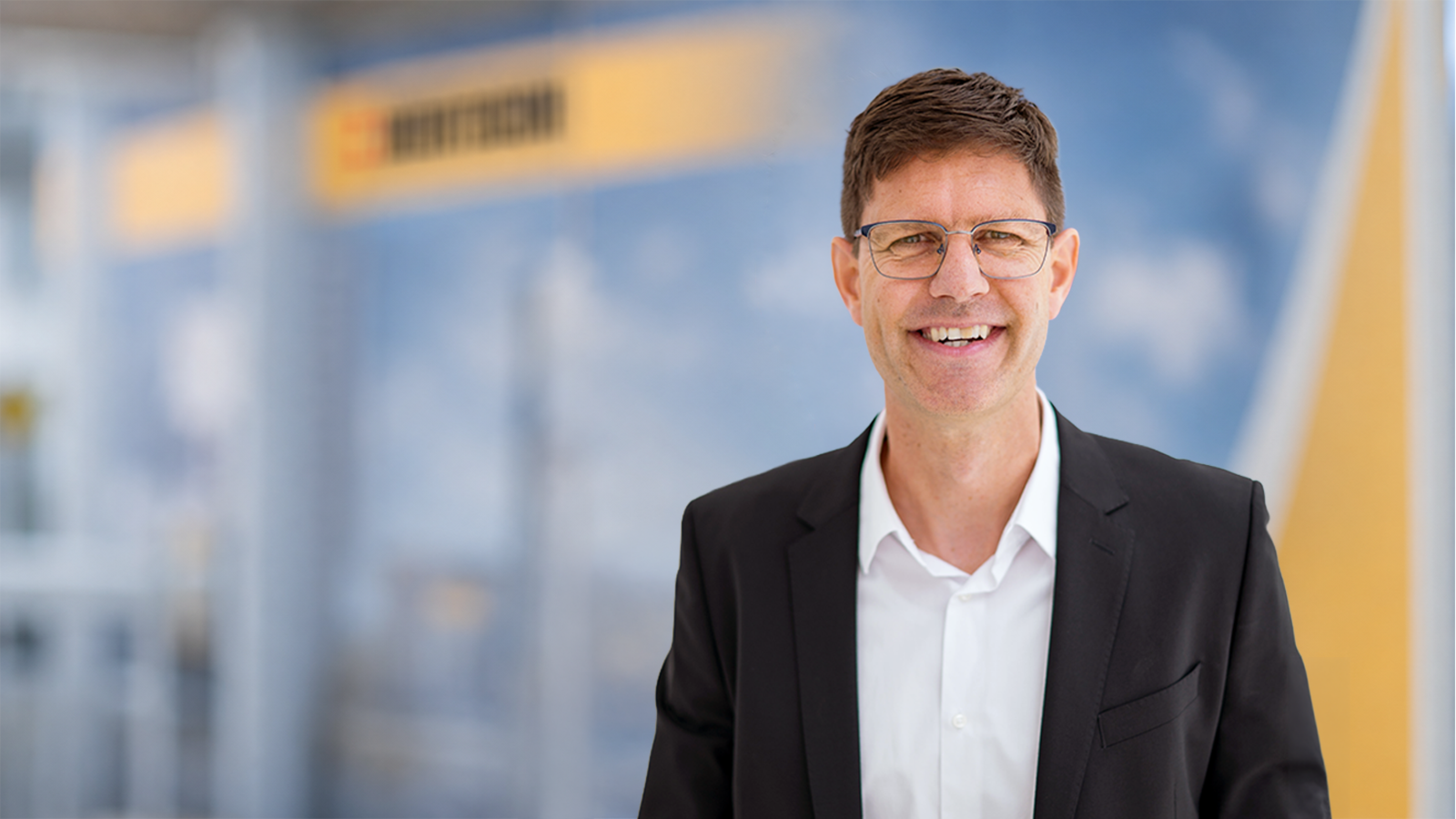 Alain Remund portrait standing in front of Bertschi background