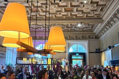 Guests gather beneath the ornate ceiling and warm lights of a Vienna networking venue.