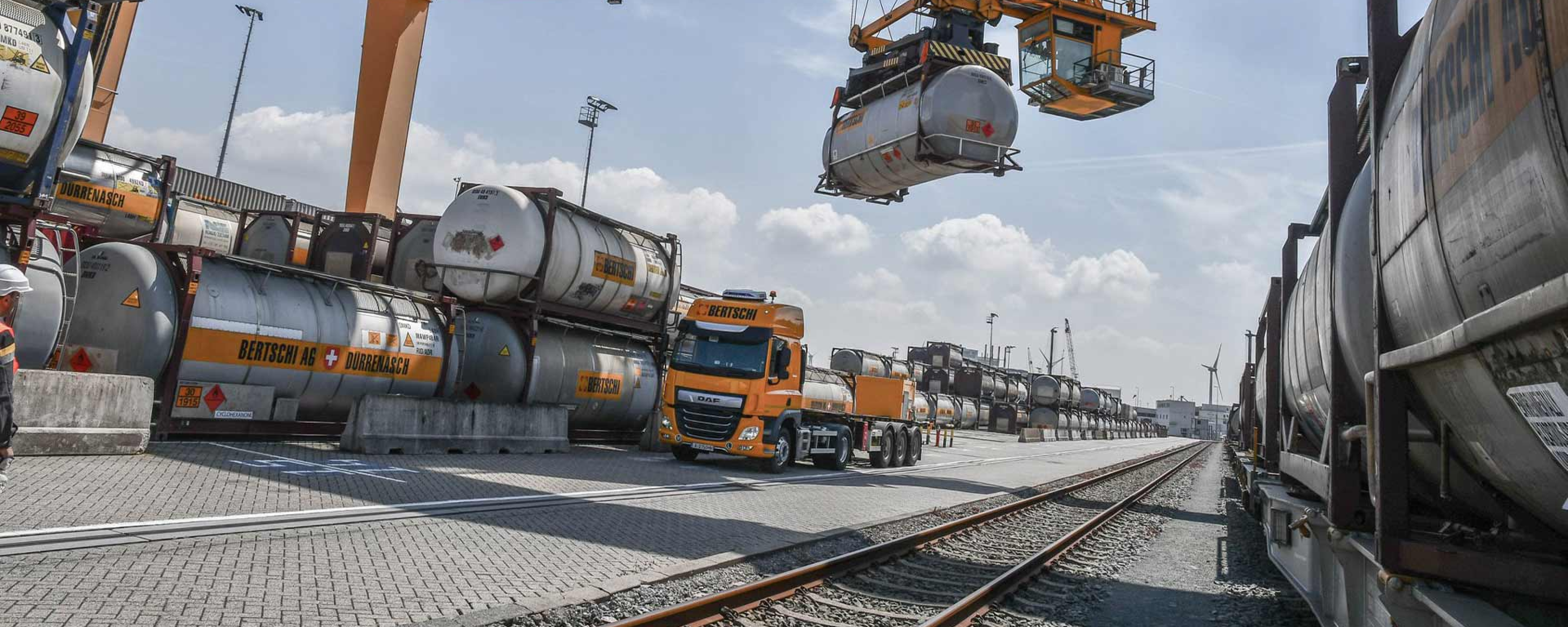 A BERTSCHI truck unloads his liquid container using a heavy lift crane.