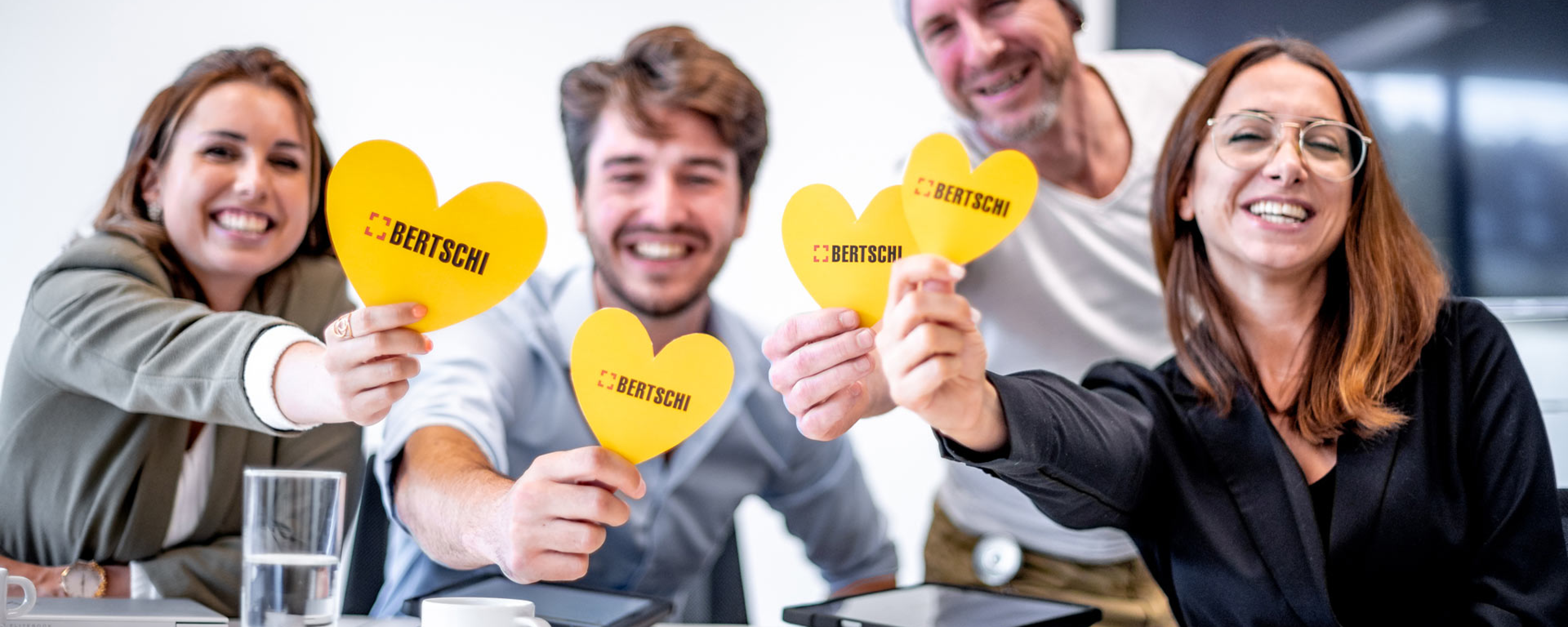 Bertschi Employees holding yellow hearts and smiling into the camera