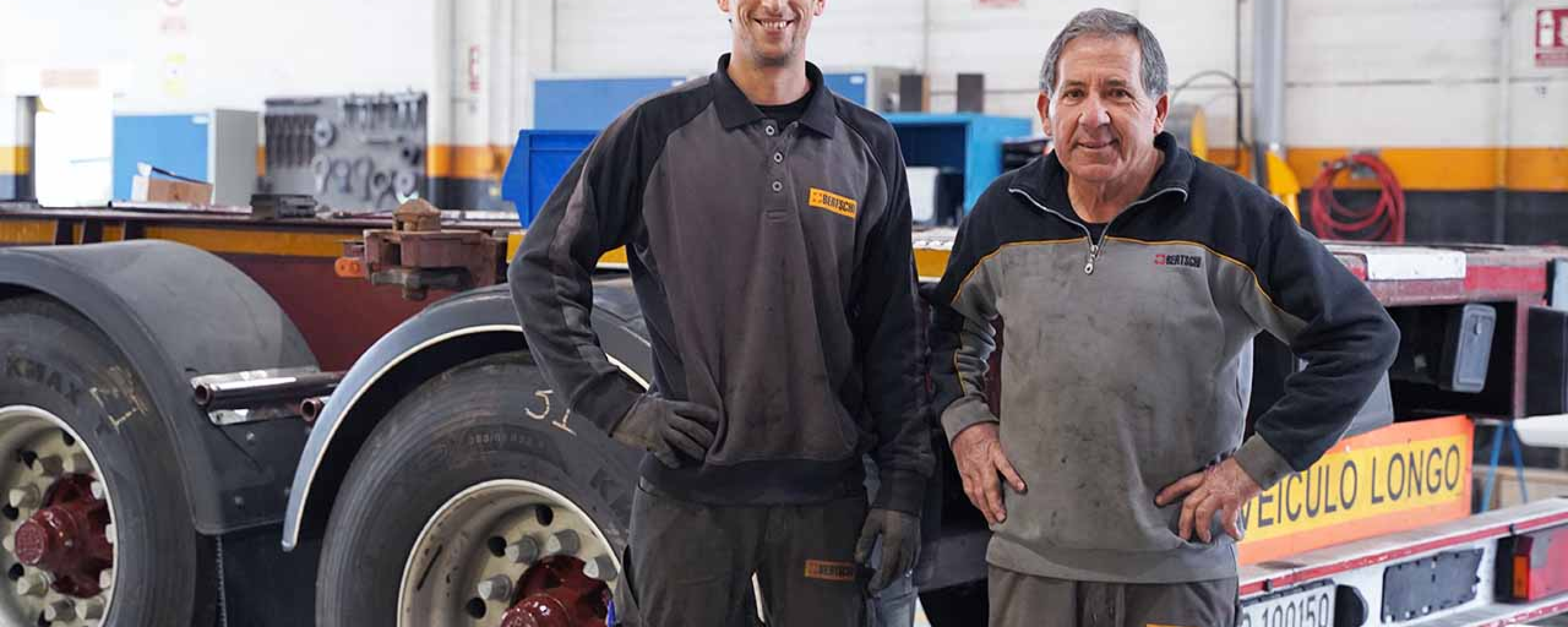 Two workshop employees in the workshop standing in front of a chassis